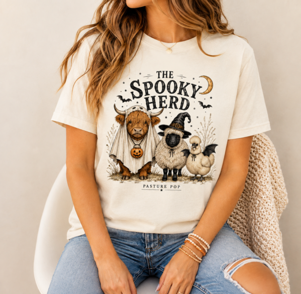 Woman wearing The Spooky Herd Tee with Highland cow, Valais Blacknose sheep, and Silkie Halloween design