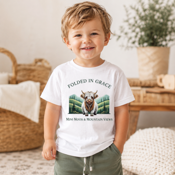 Toddler wearing the Mini Moos & Mountain Views white Highland cow graphic tee by Folded in Grace