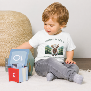 Toddler playing in a white Mini Moos & Mountain Views Highland cow graphic tee by Folded in Grace