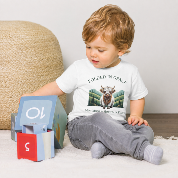 Toddler playing in a white Mini Moos & Mountain Views Highland cow graphic tee by Folded in Grace