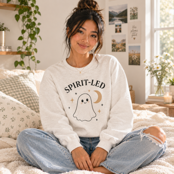 Woman wearing the Spirit-Led Ghost Crewneck with relaxed jeans in a bright, cozy bedroom.
