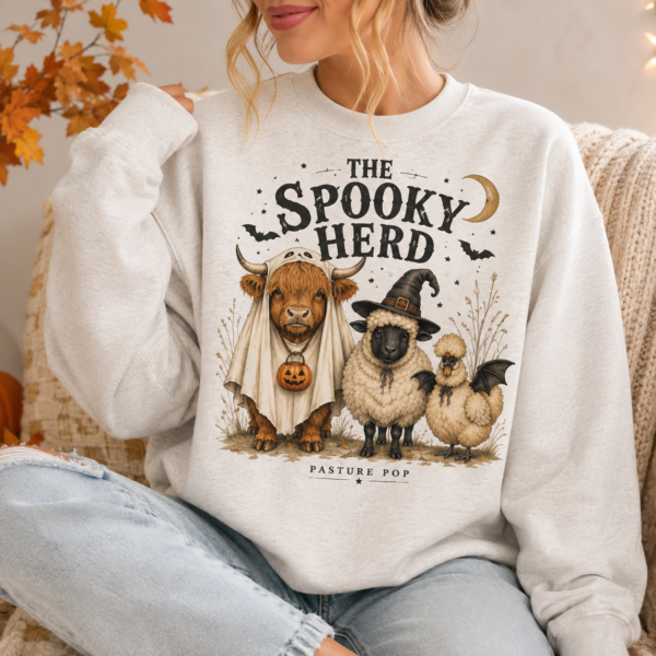 Woman wearing The Spooky Herd Crewneck with Highland cow, Valais Blacknose sheep, and Silkie Halloween design