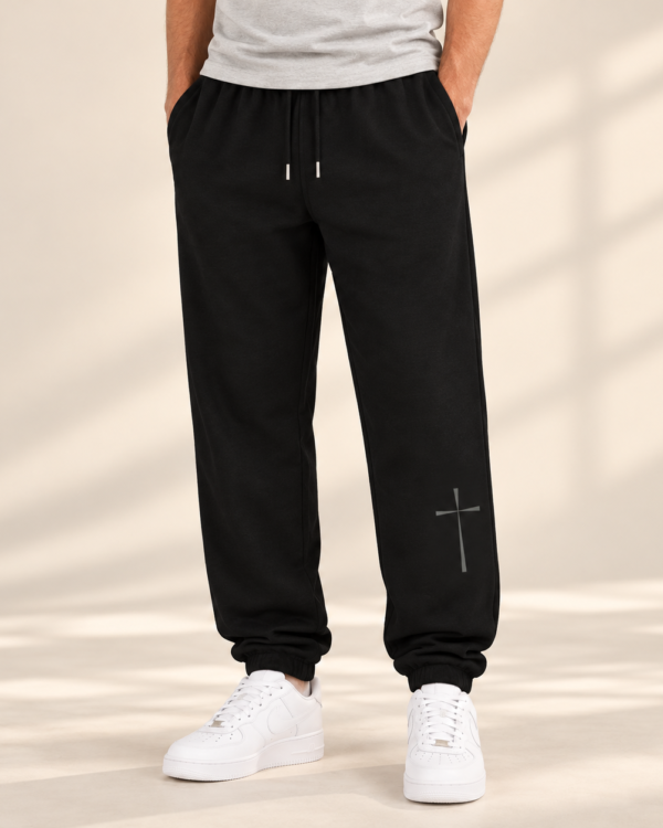 Black UNMUTED Cross Urban Sweatpants on male model with subtle gray cross design on lower leg