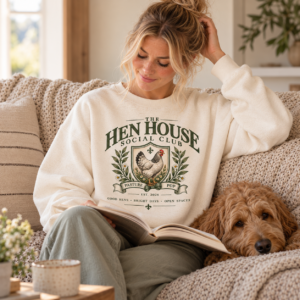 Woman wearing The Hen House Social Club cream crewneck while relaxing at home with a dog